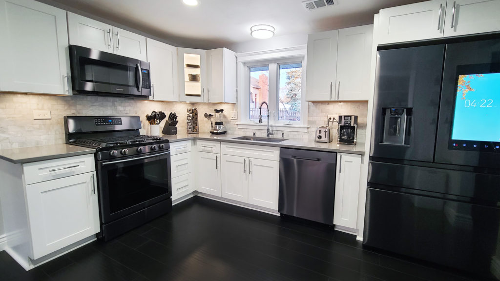 Modern kitchen with shaker white cabinets, black stainless steel appliances, and quartz countertop